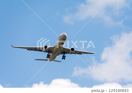 青空の下を上昇していく旅客機　ロンドン郊外のヒースロー空港近くにて 129180683