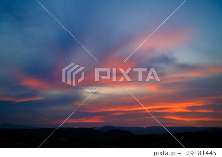 Vibrant sunset over mountain silhouettes with dramatic clouds and a colorful twilight sky 129181445