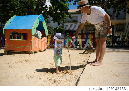 Mother and Child Play Together at a Sandy Playground on a Sunny Day 129182488