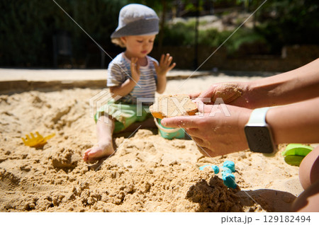Child Playing in Sand with Parental Interaction on a Sunny Day Child Playing in Sand with Parental Interaction on a Sunny Day 129182494