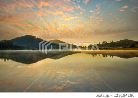 The riverside village and mountains reflect the water in the misty morning at Lake Wolfgang, Austria. 129184180