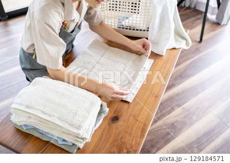 洗濯物を丁寧に畳む主夫の手元 129184571