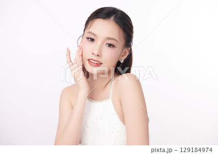 A beautiful young Asian woman with clean, fresh skin against a white background. Skincare, facial treatment, cosmetology, beauty, and spa. An elegant portrait of an Asian woman. 129184974