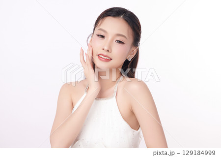 A beautiful young Asian woman with clean, fresh skin against a white background. Skincare, facial treatment, cosmetology, beauty, and spa. An elegant portrait of an Asian woman. A beautiful young Asian woman with clean, fresh skin against a white background. Skincare, facial treatment, cosmetology, beauty, and spa. An elegant portrait of an Asian woman. 129184999
