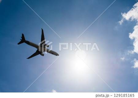 まぶしい太陽と青空の下を通過していく旅客機 ロンドン郊外のヒースロー空港近くにて まぶしい太陽と青空の下を通過していく旅客機 ロンドン郊外のヒースロー空港近くにて 129185165