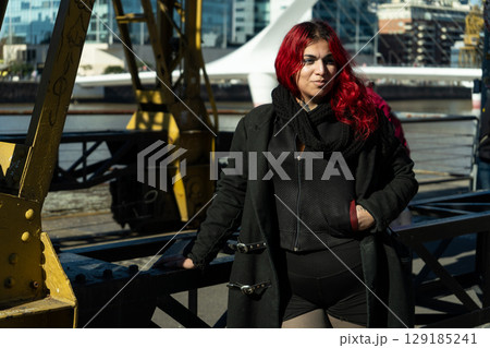 Young woman with dyed red hair posing near the woman's bridge in buenos aires Young woman with dyed red hair posing near the woman's bridge in buenos aires 129185241