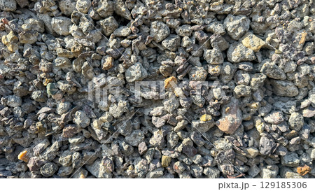 Close-up of a rough concrete wall texture with large aggregate fragments of crushed stone. Ideal as a durable industrial background. 129185306