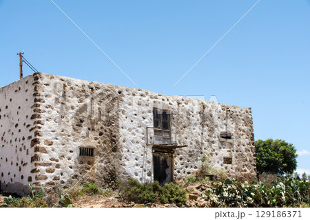 明るい日差しの中の白壁に岩を組み込んだ廃屋　フエルテベンテュラ島のベタンクリアにて 129186371