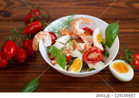 Salad with protein and greens on a wooden board 129186687