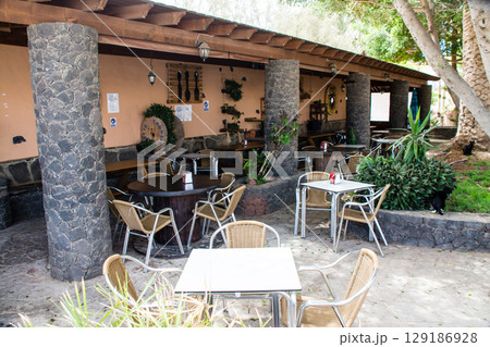 明るい日差しの下の石の柱と石畳のあるレストランのテラス　フエルテベンテュラ島のベタンクリアの街並み 129186928