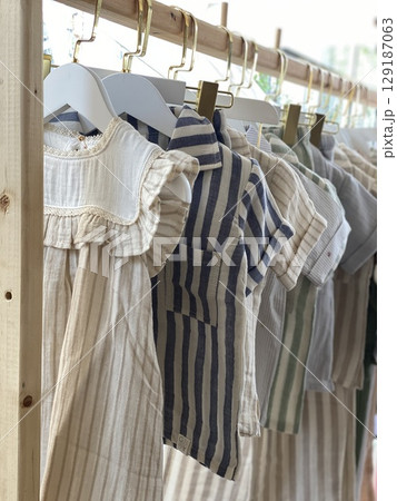 Childrens clothing on hangers with striped designs in natural tones 129187063