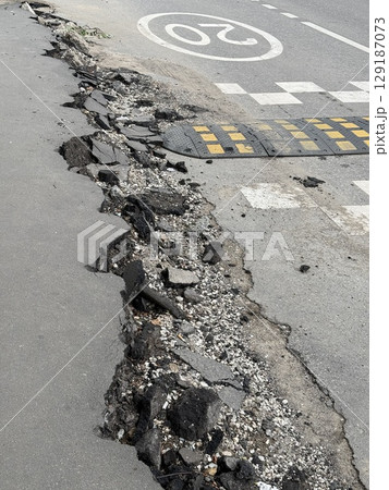 Damaged urban road with potholes near pedestrian crossing and speed bump in city Damaged urban road with potholes near pedestrian crossing and speed bump in city 129187073