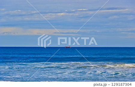 red fishing boat on a calm sea 129187304