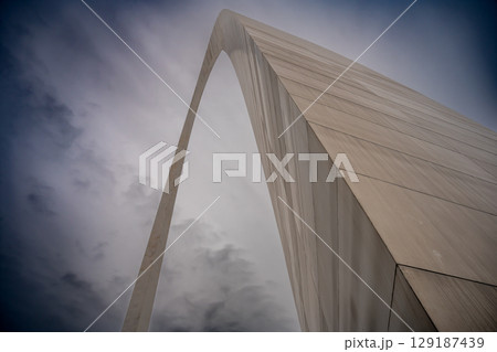 View from the base of the Gateway Arch National Park in St. Louis, Missouri showing the curve of metal against a blank sky 129187439