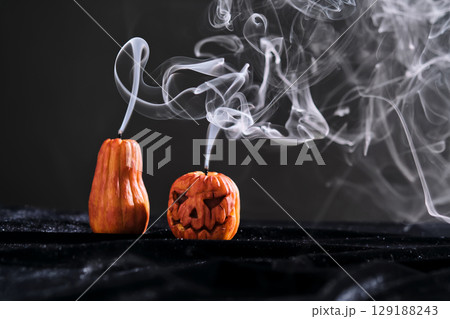 Halloween-style candles on a dark background. Festive decor. 129188243