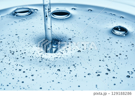 Shampoo or shower gel is poured from above and shows a bubbly texture. 129188286