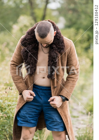 Rugged Man Outdoors: Brown Sheepskin Coat, Open Shirt, Blue Shorts, Forest Setting, Masculinity, Fall Style, Fashion, Autumnal Vibes. 129188412