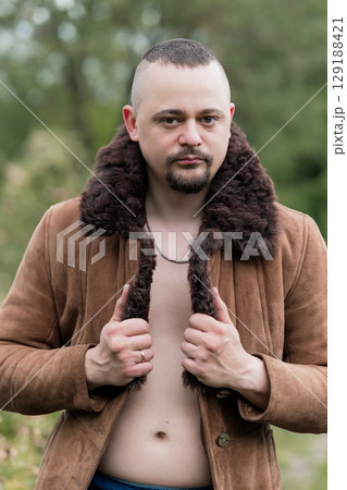 Man in Brown Suede Jacket and Fur Collar Outdoors, Rugged Look, Open Shirt, Natural Light, Forest Background, Portrait, Masculinity, Winter Fashion Man in Brown Suede Jacket and Fur Collar Outdoors, Rugged Look, Open Shirt, Natural Light, Forest Background, Portrait, Masculinity, Winter Fashion 129188421