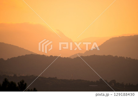 Sunrise over misty mountain layers creates a peaceful, atmospheric landscape in warm morning light. Sunrise over misty mountain layers creates a peaceful, atmospheric landscape in warm morning light. 129188430