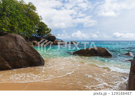 Serene Tropical Beach with Clear Waters and Large Natural Rock Formations 129188487
