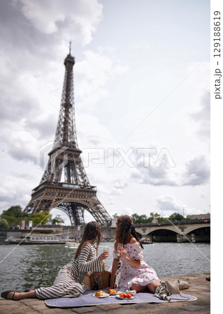 Two young women enjoying picnic on riverbank in Paris city 129188619