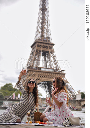 Women taking selfie during picnic by Eiffel Tower in Paris Women taking selfie during picnic by Eiffel Tower in Paris 129188631
