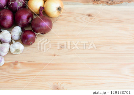 Red and yellow onions with garlic lie on a wooden background. copy space Red and yellow onions with garlic lie on a wooden background. copy space 129188701
