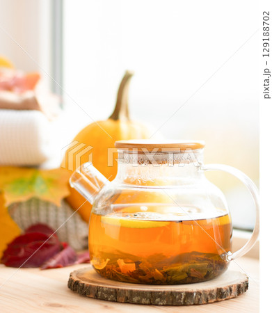 warm tea on the windowsill, cozy autumn atmosphere, pumpkin, leaves 129188702