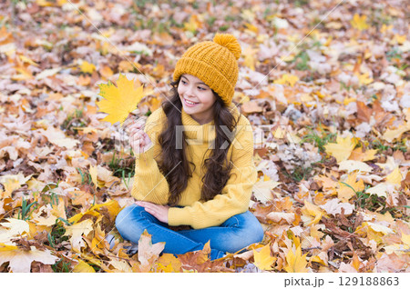 Playful mood. Warm woolen accessory. Girl long hair happy face fall nature background. Keep you warmest this autumn. Child in yellow hat outdoors. Hat keep warm. Kid wear warm soft knitted hat Playful mood. Warm woolen accessory. Girl long hair happy face fall nature background. Keep you warmest this autumn. Child in yellow hat outdoors. Hat keep warm. Kid wear warm soft knitted hat 129188863