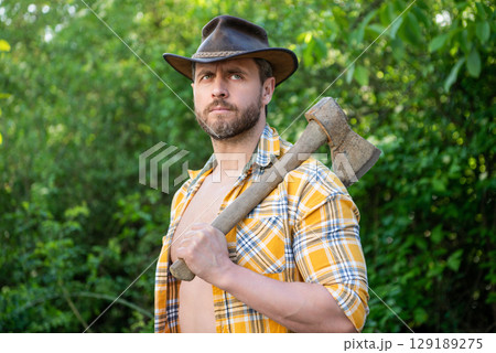 caucasian cowboy with axe wearing checkered shirt. cowboy with axe outdoor. 129189275