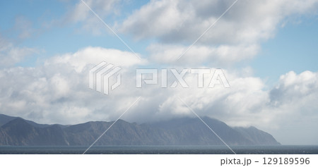 Coastal cloudscape with thick clouds hanging over mountains on the coast, New Zealand Coastal cloudscape with thick clouds hanging over mountains on the coast, New Zealand 129189596