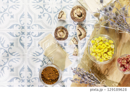 Natural, homemade, herbal tea from wild plants, flowers and mushrooms. Home herbal apothecary concept. Eco friendly composition with natural flowers, herbs, mushrooms and paper tea bags on tile table 129189628