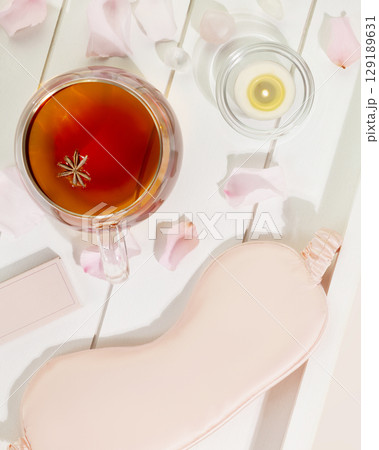 Sleep care composition with mask for sleep, cup of tea, candle and rose petals on a white wooden tray. Insomnia or depression treatment for sleepless nights. Concept of relax, self care and me time Sleep care composition with mask for sleep, cup of tea, candle and rose petals on a white wooden tray. Insomnia or depression treatment for sleepless nights. Concept of relax, self care and me time 129189631
