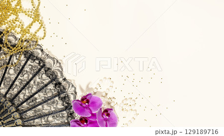 Mardi gras holiday background with black fan, golden beads, orchids and confetti with copy space. Mardi gras carnival. Flat lay 129189716