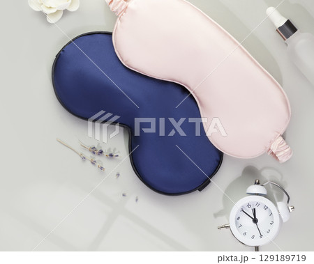 Sleep care composition with masks for sleep, alarm clock with time for sleep, oil and lavender flowers on grey background. Insomnia or depression treatment for sleepless nights. Mode for good sleep Sleep care composition with masks for sleep, alarm clock with time for sleep, oil and lavender flowers on grey background. Insomnia or depression treatment for sleepless nights. Mode for good sleep 129189719