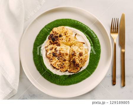 Cauliflower steak with green and white puree. Grilled cauliflower as vegan and vegetarian food concept. Healthy food ideas and menu. 129189805