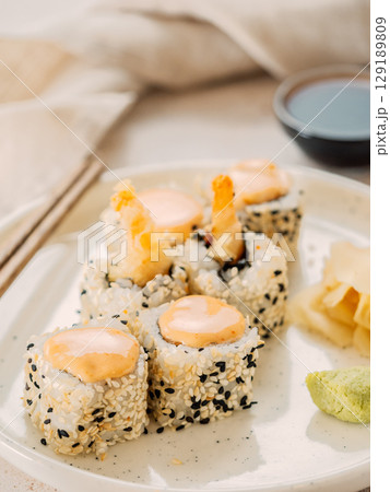 Tempura shrimp sushi roll - japanese food style on white plate over serving table. Shrimp tempura roll maki sushi Tempura shrimp sushi roll - japanese food style on white plate over serving table. Shrimp tempura roll maki sushi 129189809
