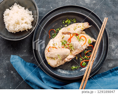 Sous Vide Chicken with spices. Boiled chicken sous-vide on black plate served with boiled rice. Sous-vide is culinary method of long-term cooking. Top view. 129189847