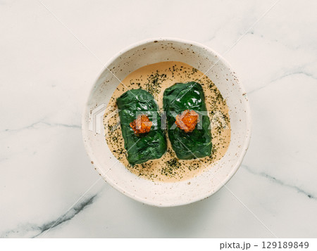 Stuffed green cabbage rolls with sauce in restaurant-style plating, served red caviar Stuffed green cabbage rolls with sauce in restaurant-style plating, served red caviar 129189849