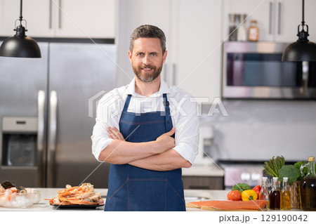 Man cook healthy food in apron. Cooking at home. Mature professional man cook healthy food. Home cuisine. Cooking healthy food. Chef man hold crossed hands. High professional 129190042