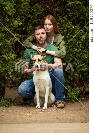 Couple enjoying outdoor time with their loyal dog in a green forest 129190074