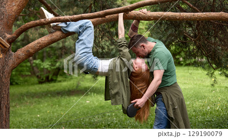 Couple enjoying a playful moment together in a lush green park 129190079