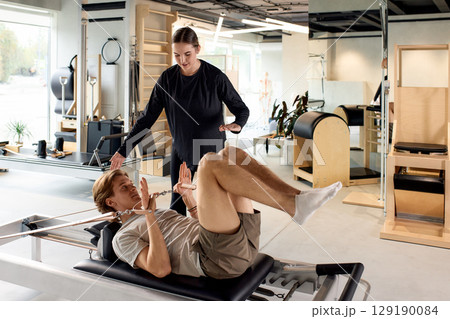 Personal training session using pilates equipment in a modern fitness studio 129190084