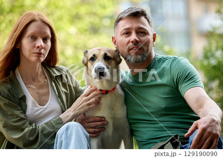 Couple enjoying time outdoors with their dog on a sunny day Couple enjoying time outdoors with their dog on a sunny day 129190090