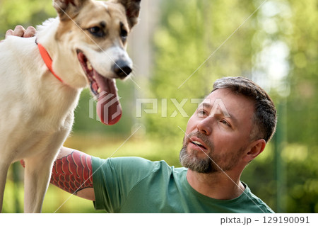 Smiling man bonding with a happy dog outdoors on a sunny day Smiling man bonding with a happy dog outdoors on a sunny day 129190091