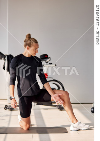 Woman stretching on a yoga mat indoors during a fitness session 129190120