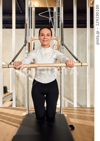 Woman practicing pilates on equipment in a modern fitness studio 129190180