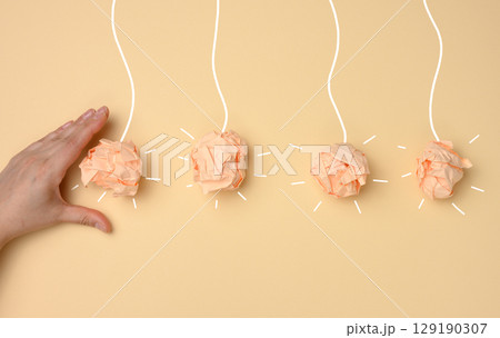 Launching a new idea or beginning a process. The hand gives a push to the first of four crumpled balls of paper, creating a chain reaction or momentum for subsequent actions. 129190307