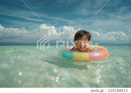 カラフルな浮き輪で遊ぶ男の子の笑顔と夏の海景色　　　　　　　　　 129190613