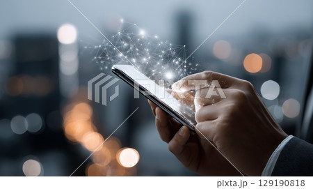Businessman navigating smartphone, glowing network hologram projecting from screen against blurred nighttime cityscape, representing global digital Professional businessman 129190818